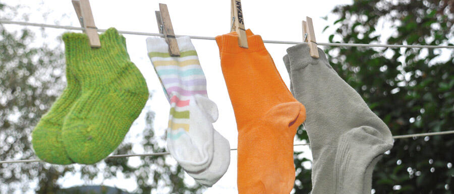 4 Paar bunte Socken von Kindern und Erwachsenen hängen auf einer Wäscheleine © Robin Menges